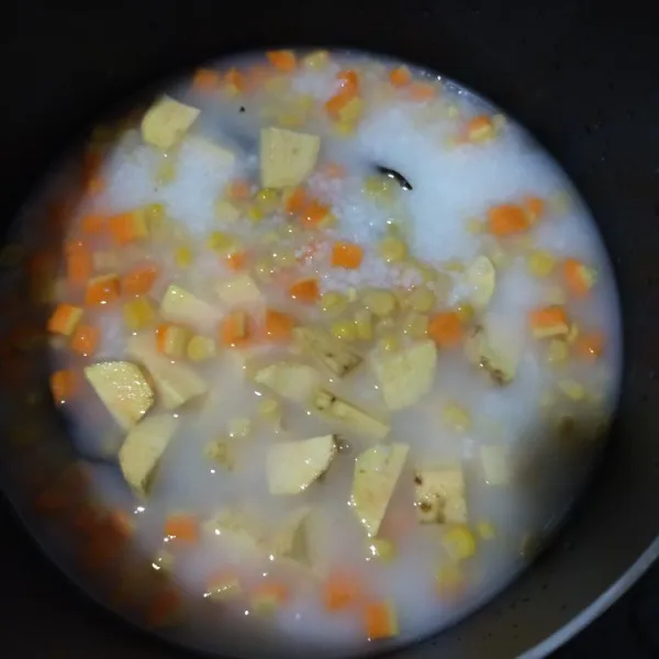 Masukkan ke dalam panci blenderan nasi, potongan ubi, wortel, jagung, daun salam, dan serai