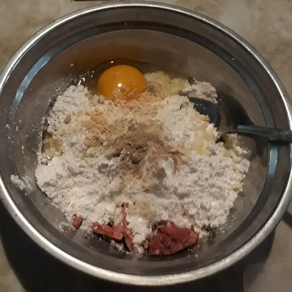 Tambahkan telur, lada bubuk, bawang putih cincang halus, garam dan kaldu jamur.