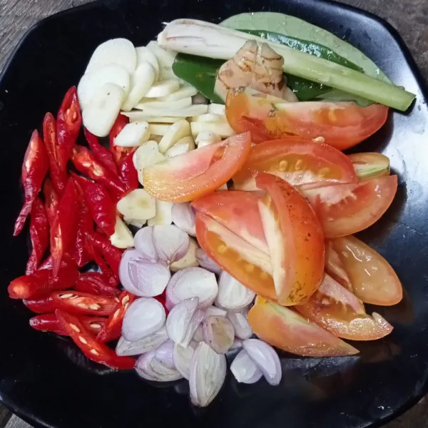 Iris tipis bawang merah dan bawang putih, potong-potong cabai dan tomat, geprek lengkuas dan serai.