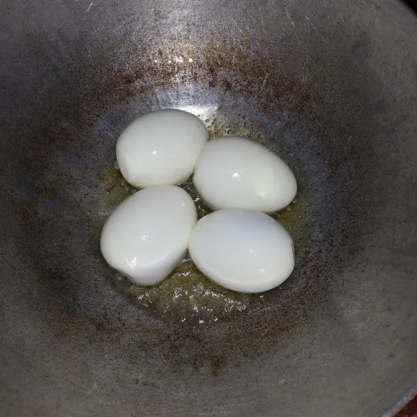 Rebus telur, kemudian kupas. Lalu panaskan sedikit minyak, goreng telur.