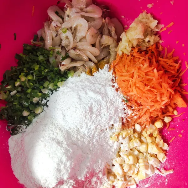 Dalam wadah berisi, jagung, udang, wortel dan daun bawang, tambahkan terigu, tepung beras, garam, lada bubuk, ketumbar bubuk, kunyit bubuk dan bawang putih halus.