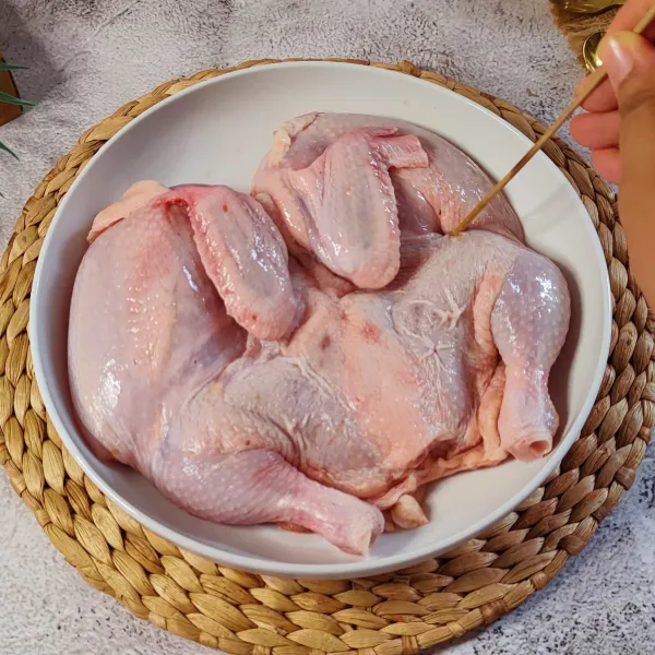 Siapkan ayam yang sudah di belah bagian dadanya, tusuk-tusuk dengan tusuk sate supaya bumbu meresap.