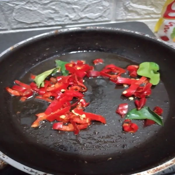 Panaskan minyak di teflon, tumis cabai merah bersama daun jeruk hingga aroma daun jeruk keluar.