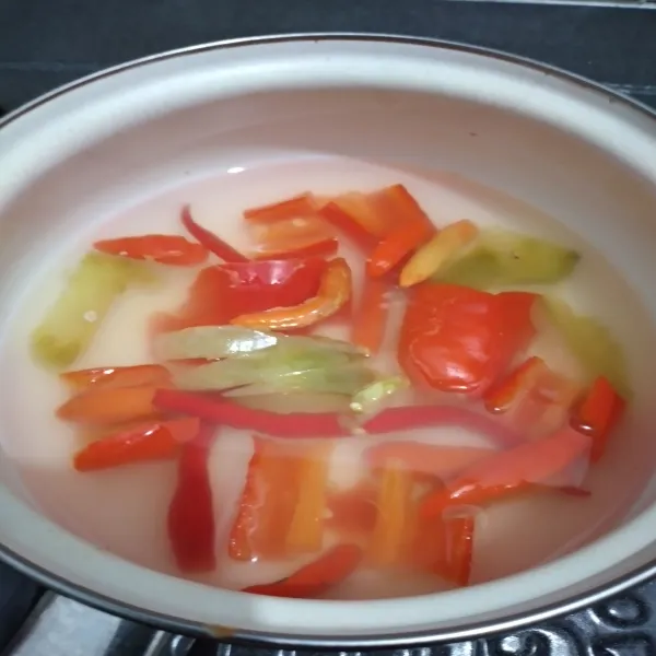 Potong dan iris cabai besar dan tomat hijau, lalu rebus hingga matang.