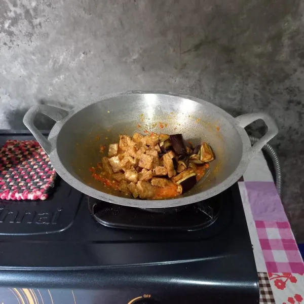 Masukkan terong dan tempe goreng, masak sampai air menyusut. Angkat dan sajikan di atas piring saji.