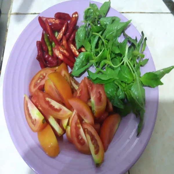Cuci tomat, cabe dan kemangi, potong tomat, iris serong cabe keriting, petik daun kemangi, buang batangnya.