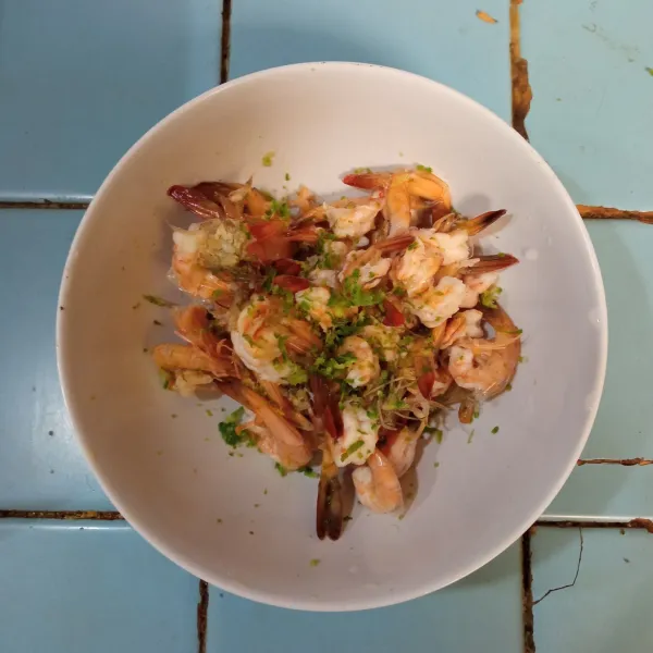 Masukkan udang ke dalam wadah, beri parutan kulit jeruk, lalu aduk.