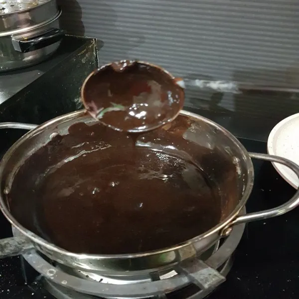 Masukkan cokelat blok ke dalam sisa adonan di panci. Nyalakan kembali api sampai cokelat mencair (tidak perlu sampai mendidih), lalu aduk rata. Tuang sedikit demi sedikit ke atas adonan milo yang sudah berkulit permukaan atasnya.