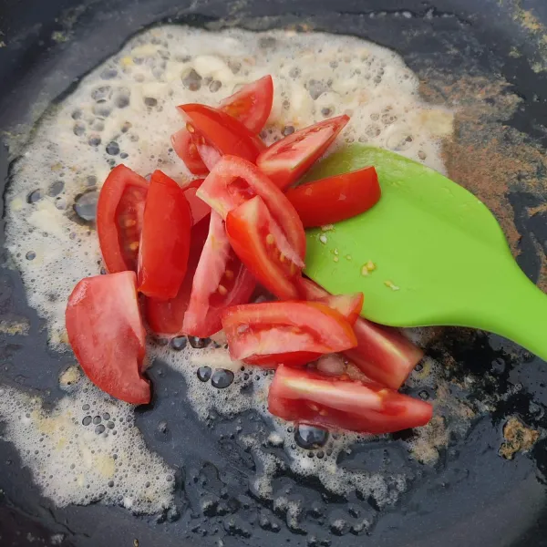 Di wajan yang sama, tumis bawang putih dengan sedikit minyak hingga harum, lalu masukkan tomat. Tumis hingga layu.