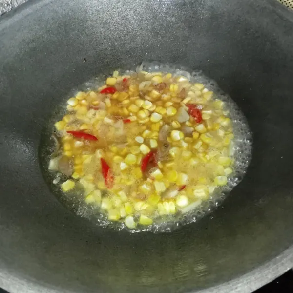 Masukkan jagung yang sudah dipipil, aduk-aduk dan tambahkan air.