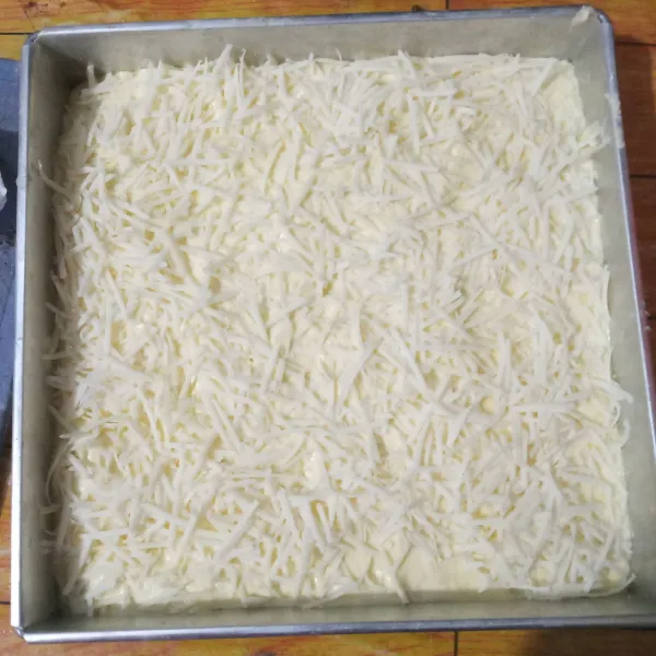 Tuang ke dalam loyang yang sudah diolesi margarin, hentakkan, lalu taburi dengan keju parut.