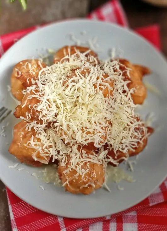 Taruh beberapa potong tape goreng di tempat saji, tambahkan susu kental manis dan taburi keju parut, kemudian sajikan.