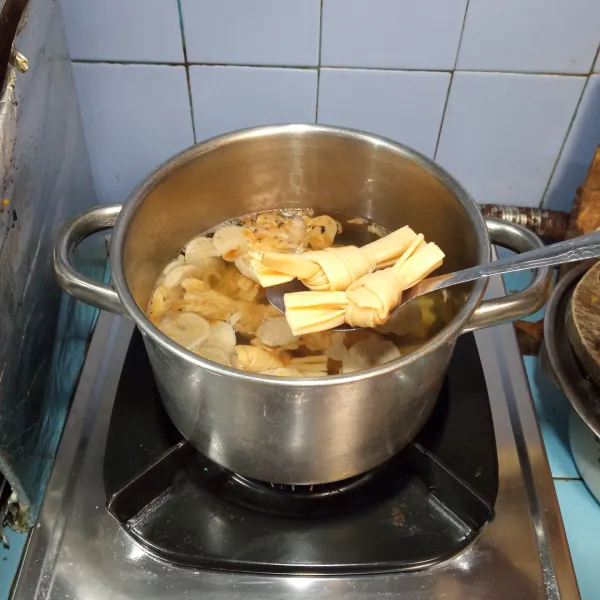 Kemudian tambahkan kembang tahu dan jamur kuping, masak hingga agak lunak.