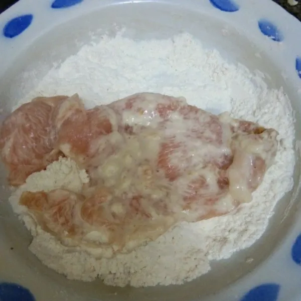 Gulingkan ayam pada tepung kering, pastikan terlumuri rata