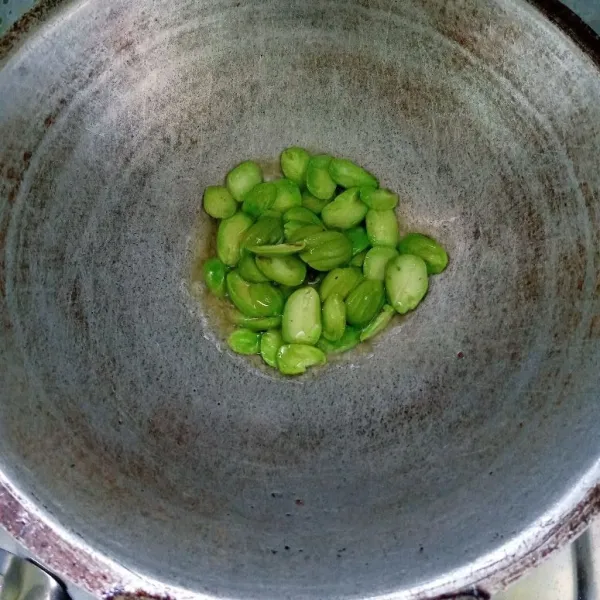 Kupas petai dan belah dua. Kemudian goreng sebentar.