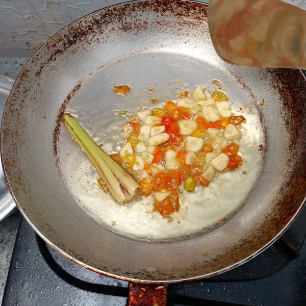 Panaskan minyak dan masukkan serai, bawang putih dan cabai rawit kecil.