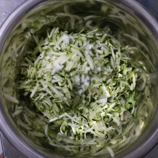 Lumuri zucchini dengan garam. Diamkan selama 15 menit, lalu peras dan buang airnya.