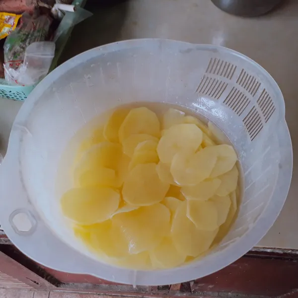 Kupas kentang, cuci bersih, iris tipis - tipis. 
Rendam kentang dengan air agar tidak berubah warna.