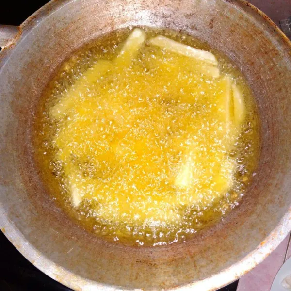 Setelah beku, goreng di minyak panas hingga setengah matang, pastikan menggoreng dengan minyak terendam. Angkat dan tiriskan, biarkan kentang dingin. Baru digoreng lagi hingga matang, lalu angkat dan tiriskan.
