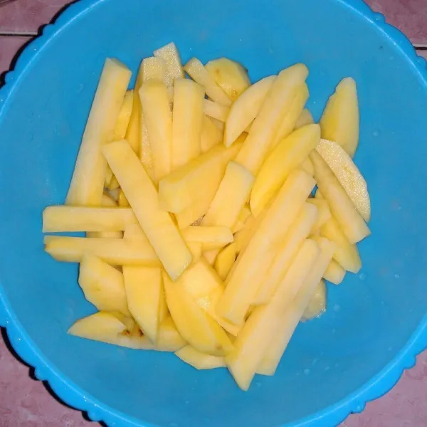 Kupas kentang dan potong memanjang dengan ketebalan sesuai selera, lalu cuci bersih hingga air rendaman menjadi bening.