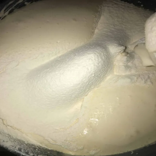 Masukkan tepung terigu dan baking powder ke dalam adonan sambil diayak.