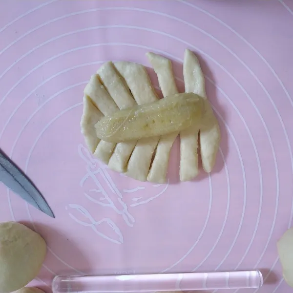 Ambil 1 buah adonan, gilas kemudian iris bagian pinggirnya bentuk rumbai-rumbai dan isi bagian tengah dengan pisang kemudian kepang.