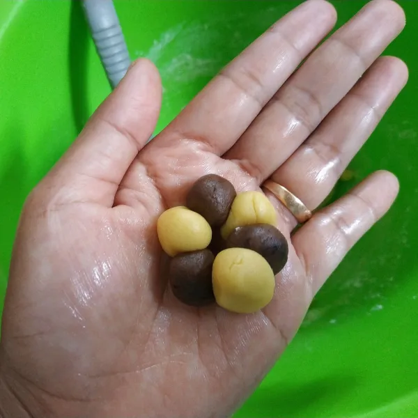 Ambil sedikit adonan putih dan coklat kemudian bentuk bulat, tata di telapak tangan secara selang-seling.