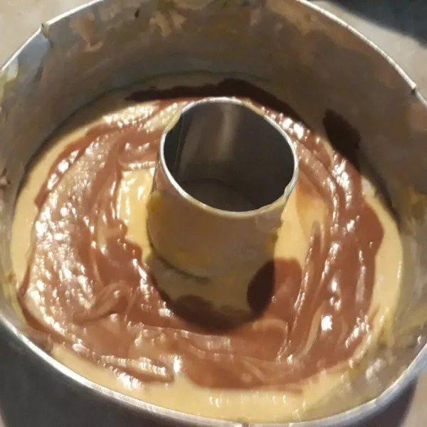Tuang adonan ke dalam loyang yang sudah diolesi mentega tipis. Sisakan sedikit campur dengan cokelat bubuk. Tuang ke dalam adonan, aduk perlahan bagian tengahnya. Panggang sampai matang.