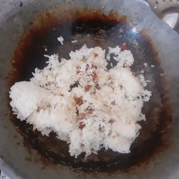 Tumis bumbu nasgor hingga harum dalam sedikit minyak panas. Tambahkan nasi.