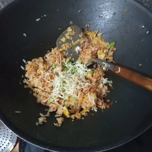 Masukkan keju parut dan irisan daun bawang.