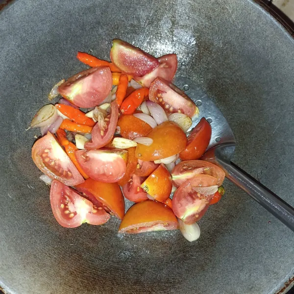 panaskan minyak lalu tumis bawang merah sampai layu. Masukkan bawang putih dan cabai, tumis sampai matang, masukkan tomat.