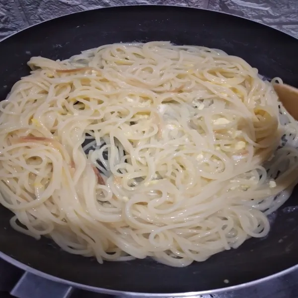 Kocok telur lalu tuang di atas spaghetti, aduk aduk cepat hingga tercampur rata, masak hingga telur matang, sisihkan.