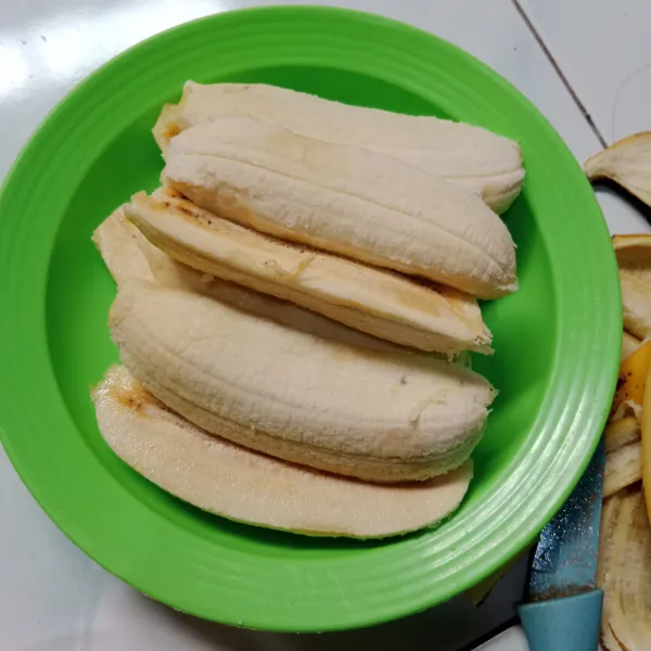 Kupas pisang dan belah jadi dua.