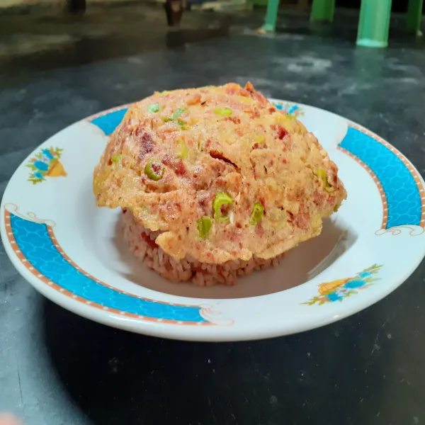 Sajikan nasi goreng dengan telur dadar di atasnya.