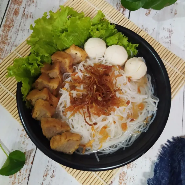 Tata di mangkuk saji, bihun beras, daun sla, teri goreng, irisan tahu bakso dan bakso ikan yang sudah direbus. Siram dengan kuah panas dan beri taburan bawang merah goreng. Sajikan.