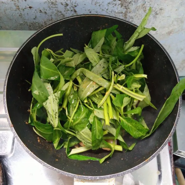 Masukkan kangkung. Aduk rata. Kemudian tutup dan masak sampai layu.