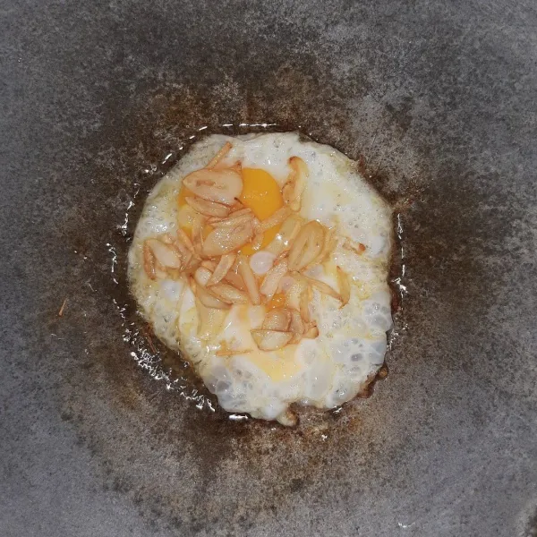 Pindahkan bawang putih ke atas telur.
