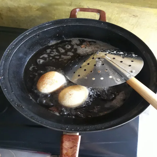 Panaskan minyak goreng dengan api besar, lalu masukkan telur rebus yang sudah dikupas. Setelah telur berkulit kecilkan api. Masak hingga matang lalu angkat dan tiriskan telur.