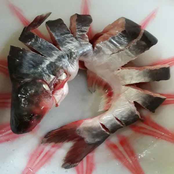 Potong tidak sampai putus bagian bagian kecil ikan patin lalu cuci bersih. Beri perasan jeruk nipis diamkan 10 menit.