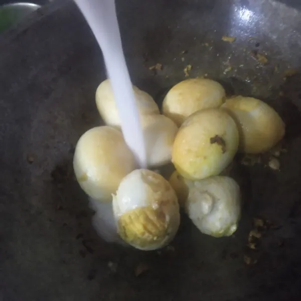 Masukkan telur, aduk sebentar agar telur sedikit tergoreng. Lalu beri santan yang sudah dicampur air.