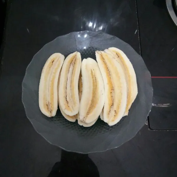 Kupas pisang, lalu belah memanjang menjadi 2 bagian.