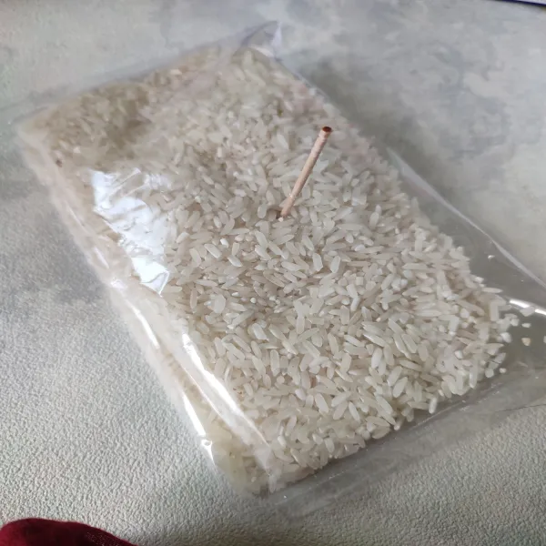 Isi plastik lontong dengan beras, isi setengah bagian saja. Kemudian rekatkan plastik dengan lilin, tusuk-tusuk plastik dengan lidi.