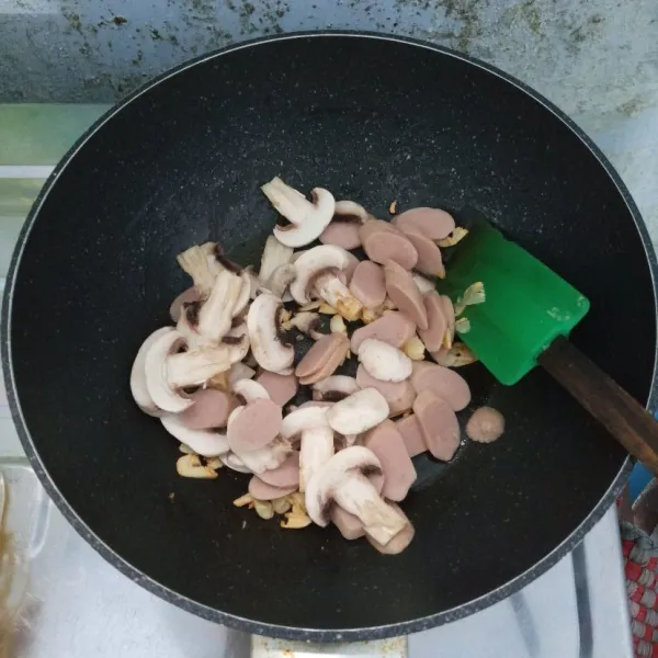 Masukkan sosis dan sayur. Aduk rata. Masak sampai jamur layu.