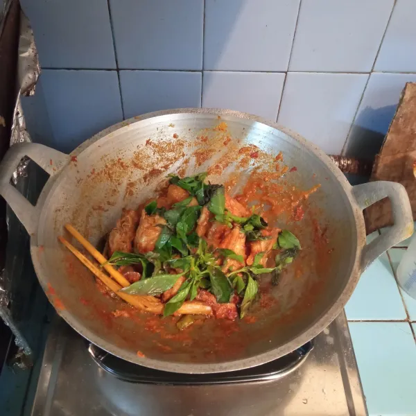 Setelah kuah mulai menyusut, tambahkan daun kemangi dan irisan daun bawang, aduk kembali, ayam masak kemangi siap disajikan.
