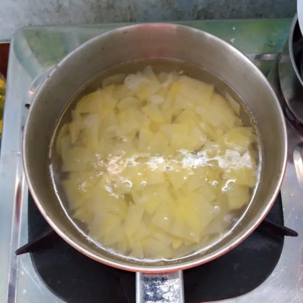 Potong-potong kentang dan iris tipis. Kemudian masukkan ke dalam air mendidih. Rebus sebentar sampai mendidih. Angkat dan tiriskan.