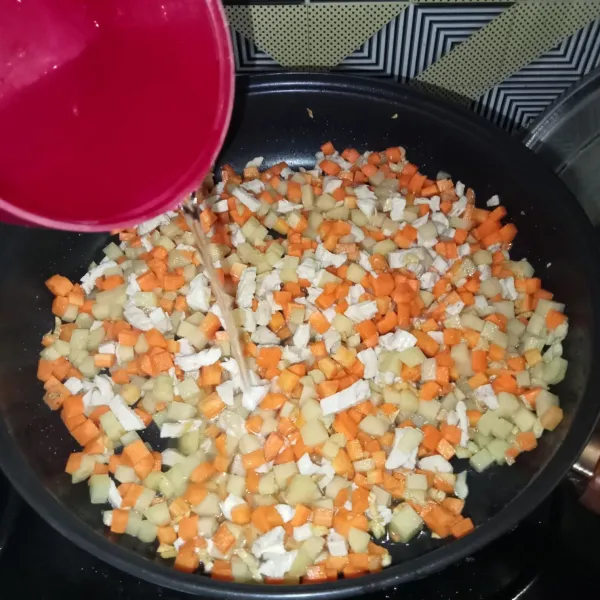 Masukkan kentang, wortel dan ayam, aduk rata. Tuang air dan bumbui dengan garam, lada bubuk, dan kaldu jamur.