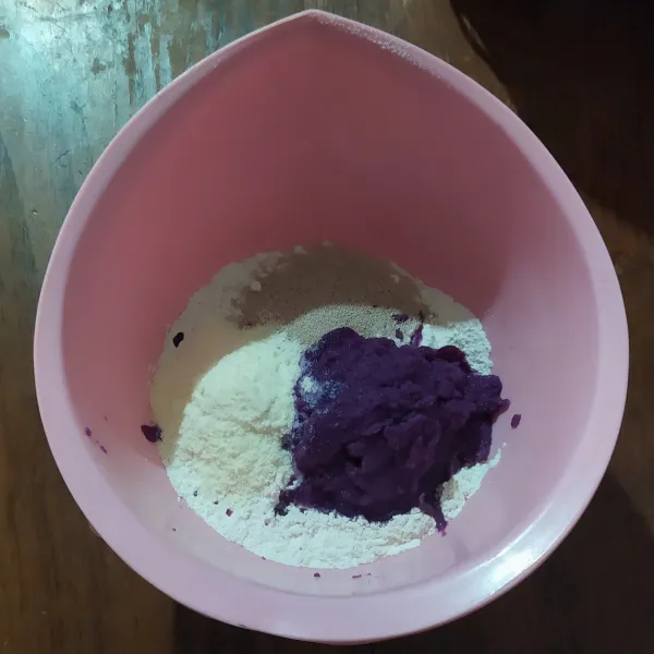 Blender ubi ungu dan air. Masukkan ke dalam wadah berisi terigu, gula, susu bubuk dan ragi instan, kemudian mixer dengan speed rendah supaya tercampur.