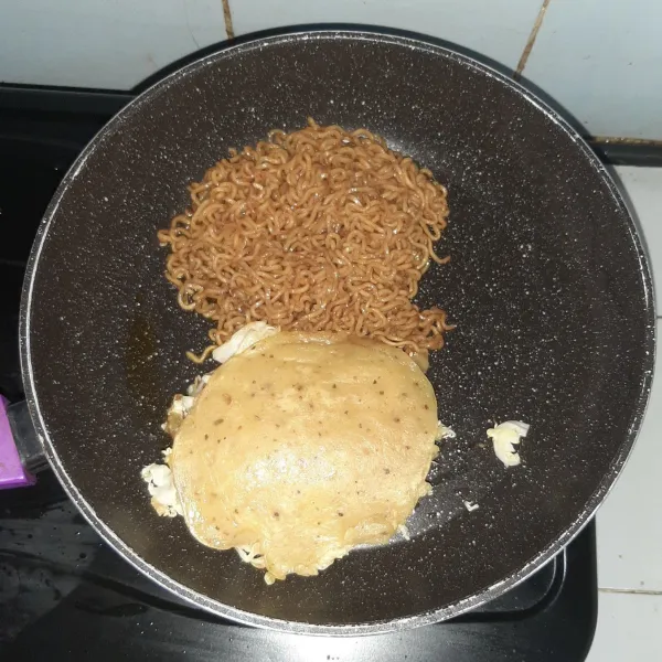 Sambil memasak smoked beef, tumis mie goreng agar sedikit krispy lalu tumpuk adonan utama ke atas mie.