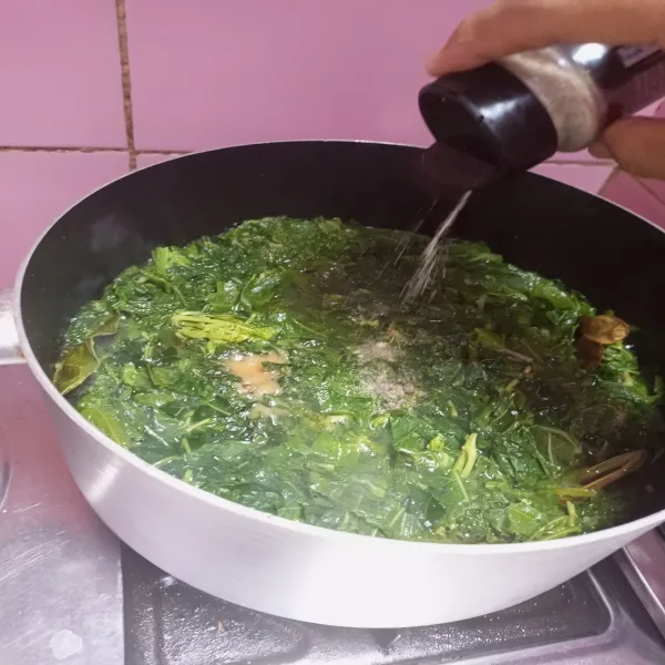 Masukkan daun singkong, lalu bumbui dengan garam, kaldu jamur, dan lada bubuk. Masak hingga bumbu meresap.