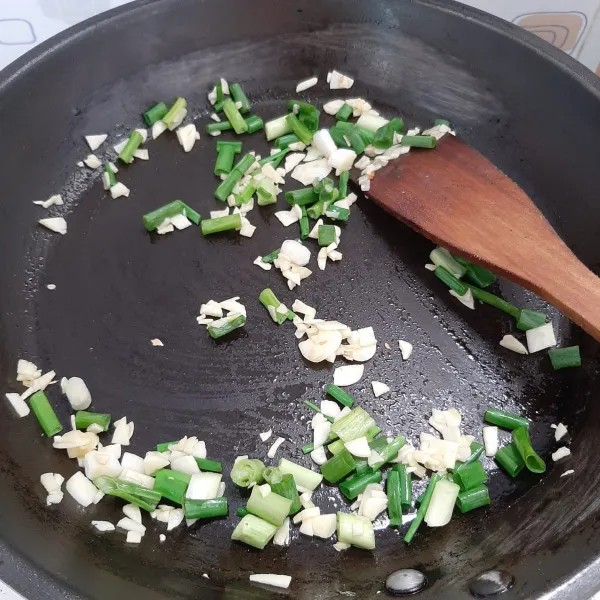 Tumis bawang putih hingga harum, lalu tambahkan daun bawang, aduk rata.